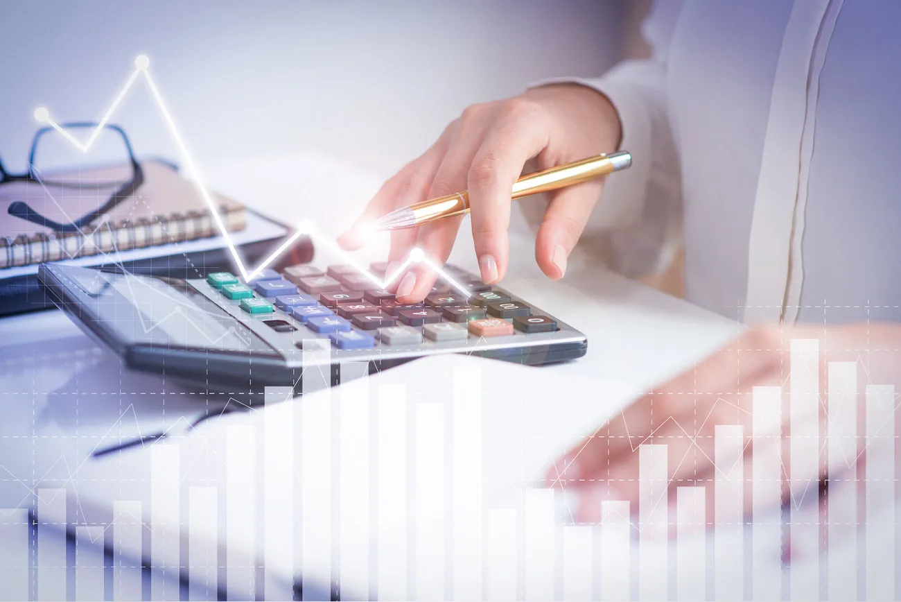 Profesional utilizando una calculadora frente a gráficos de análisis financiero.