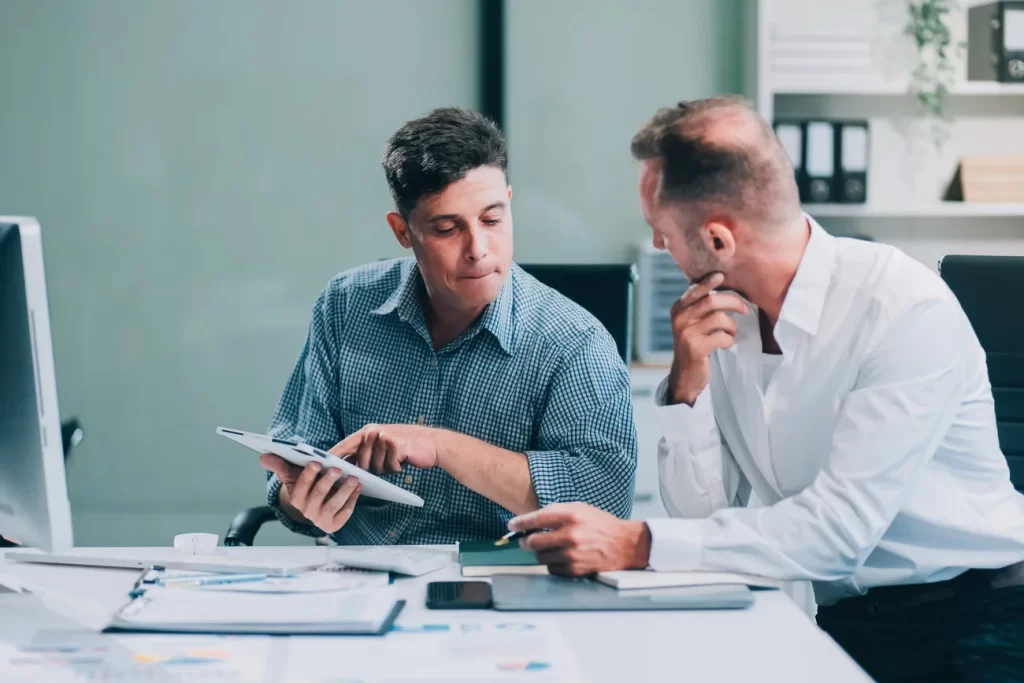 Dos profesionales calculando presupuesto, impuestos y resultados de una empresa.