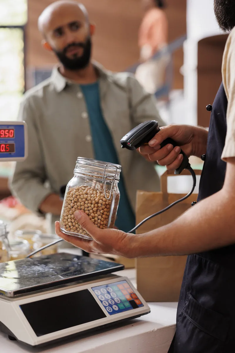 Trabajador registrando un producto con lector en un comercio.