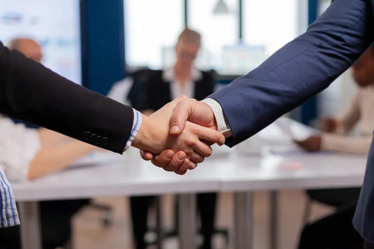 Representante de empresa estrechando la mano de un nuevo trabajador.