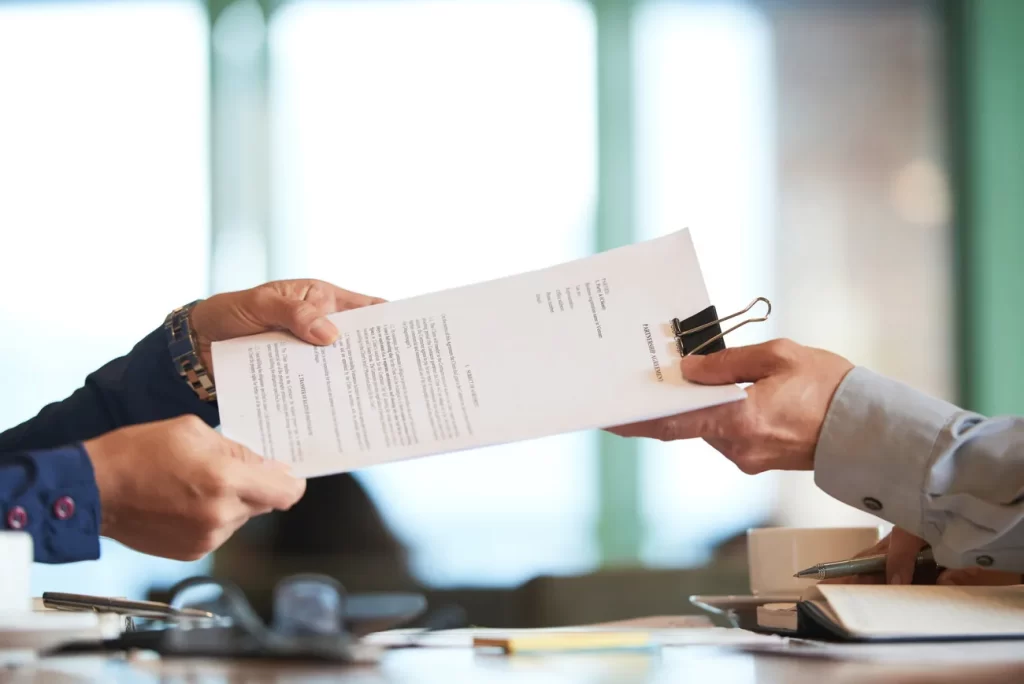 Entrega de un contrato entre profesionales durante una reunión de empresa.