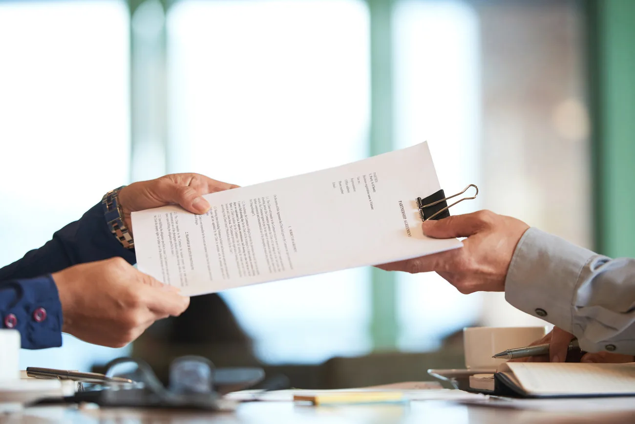 Entrega de un contrato entre profesionales durante una reunión de empresa.