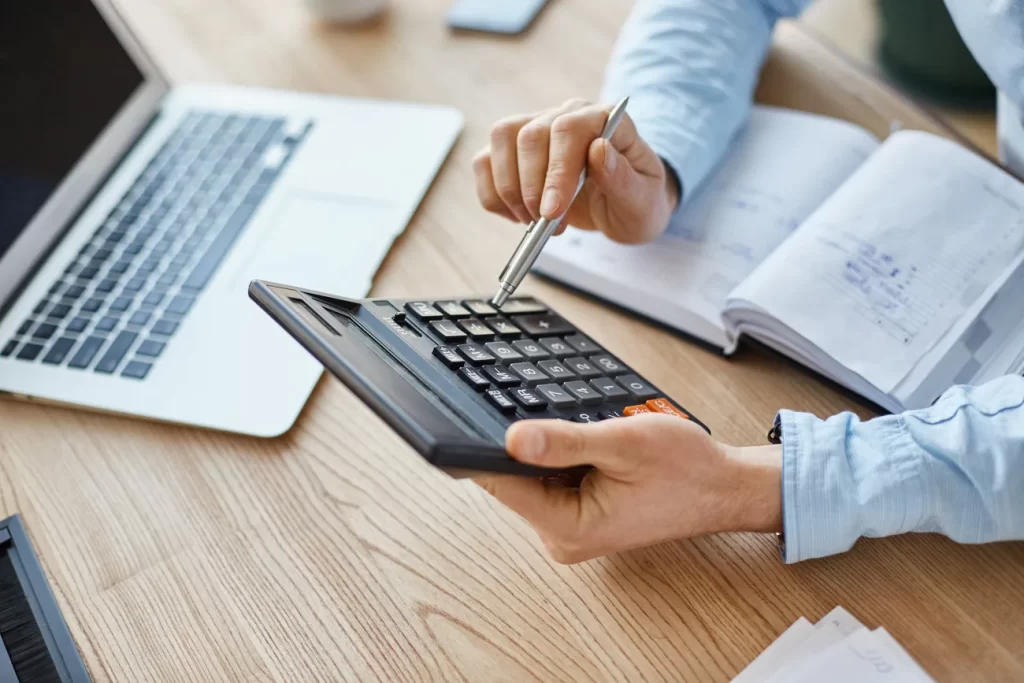 Profesional revisando cifras con calculadora y documentación financiera.