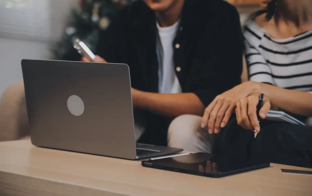 Equipo de trabajo conversando alrededor de un computador portátil.