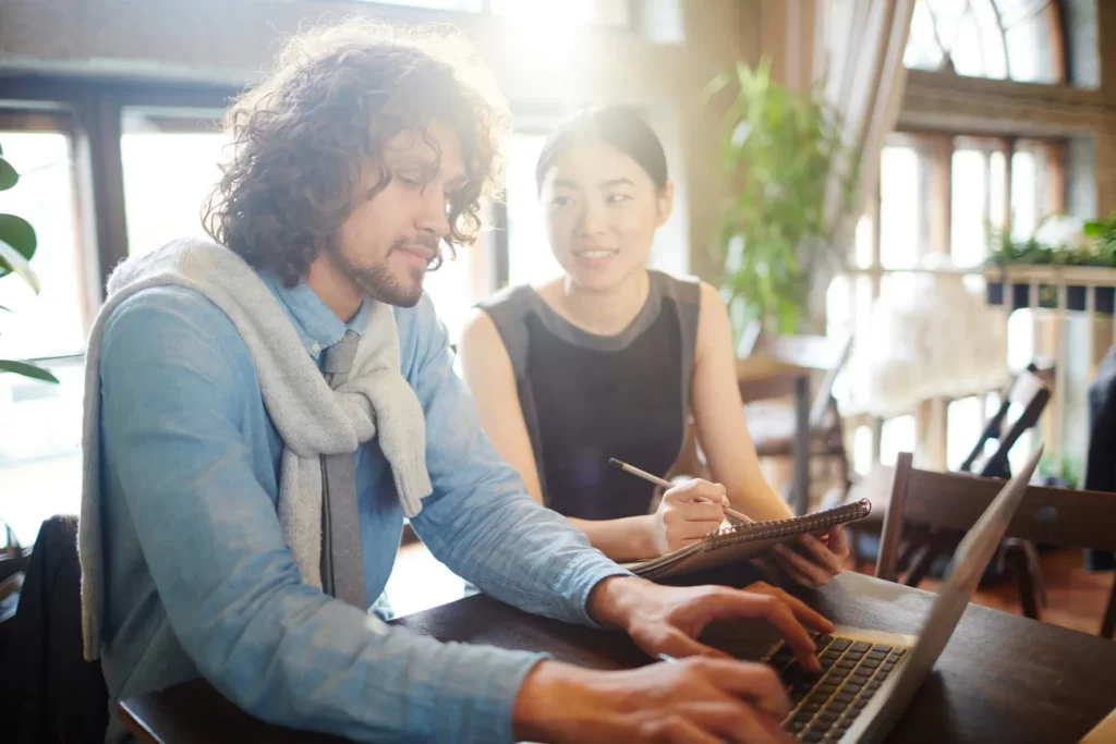 Dos profesionales trabajando juntos con un computador portátil.
