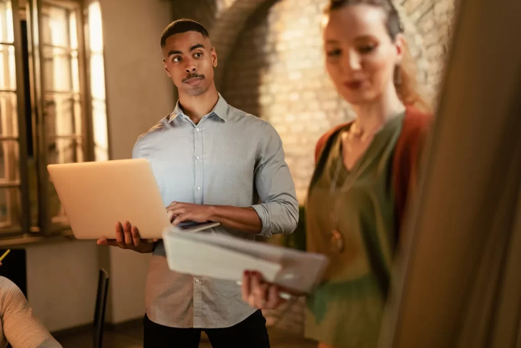 Profesionales colaborando con computador y documentación en una oficina.