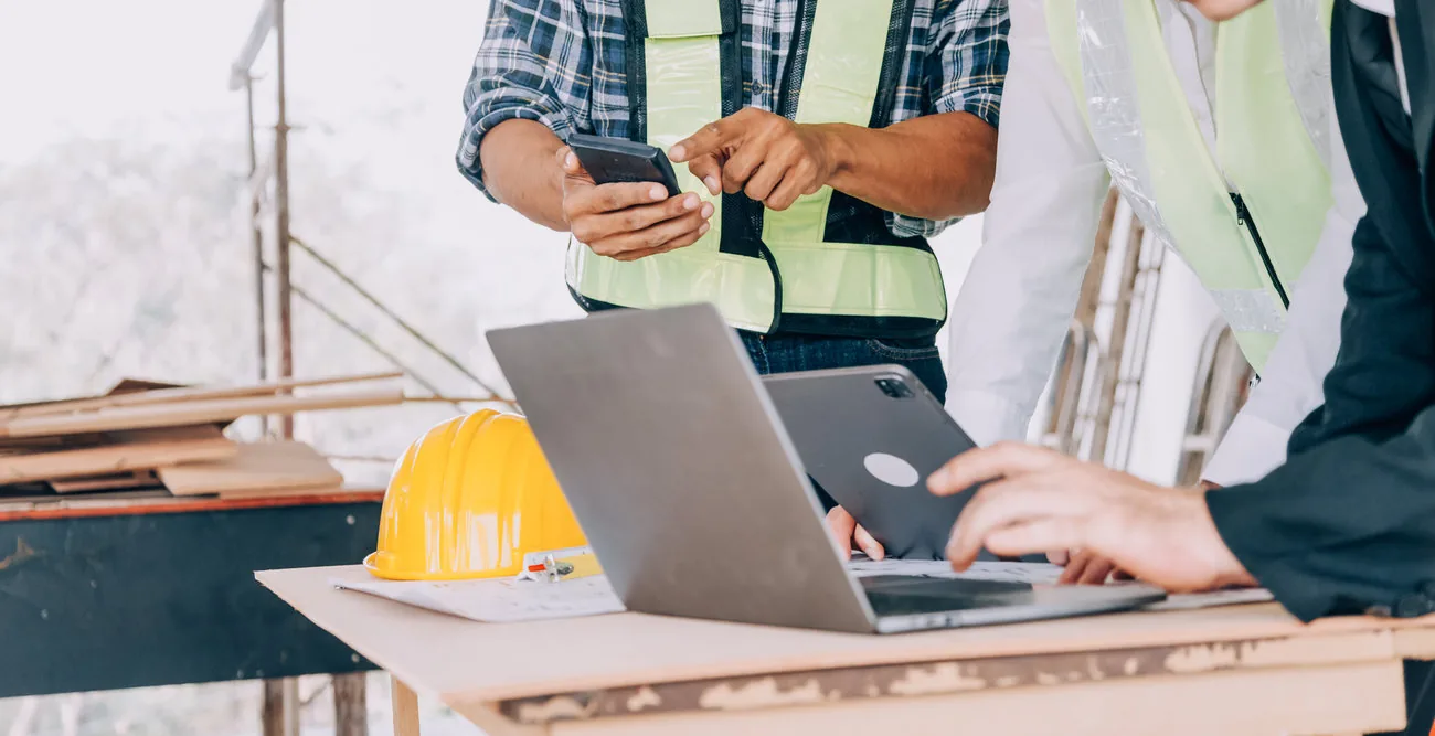 Equipo de construcción revisando información en una tablet dentro de una obra.
