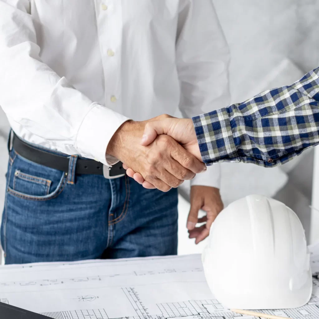 Dos profesionales estrechando las manos en un contexto de construcción.