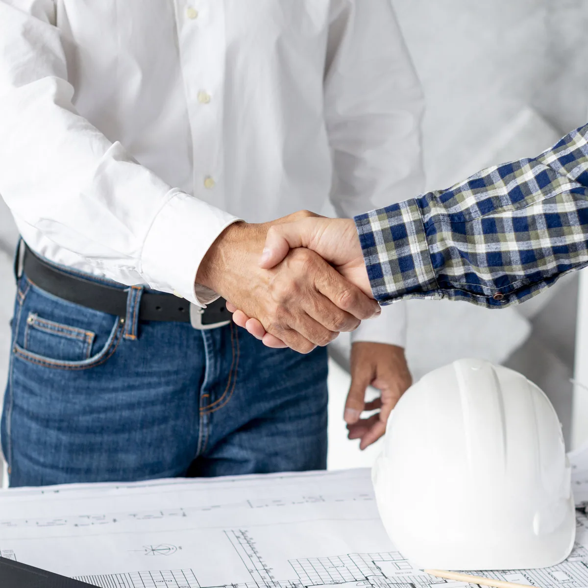 Dos profesionales estrechando las manos en un contexto de construcción.