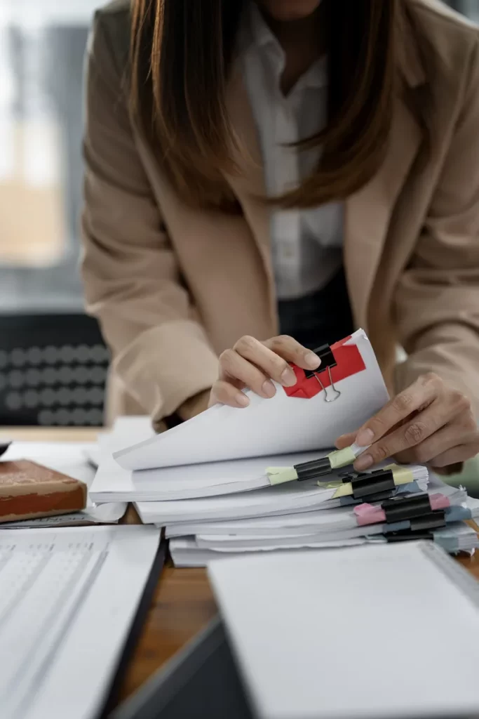 Profesional ordenando y revisando una gran cantidad de documentos de oficina.