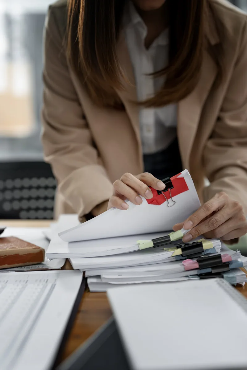 Profesional ordenando y revisando una gran cantidad de documentos de oficina.