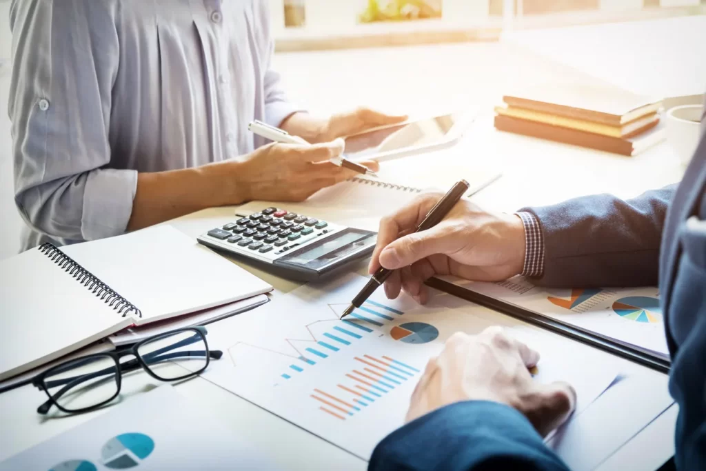 Profesionales revisando cálculos, documentos y reportes financieros.