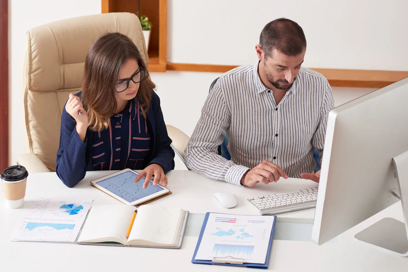 Dos profesionales revisando reportes y gráficos financieros.